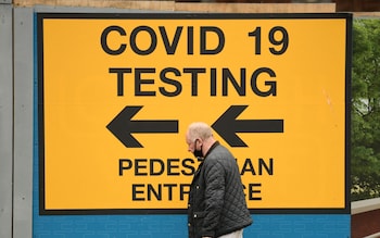 A pedestrian walks past a sign directing members of the public to a Covid-19 testing centre in Bolton, north west England