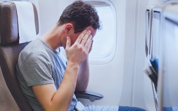 Tired man on plane, travel mistakes to avoid