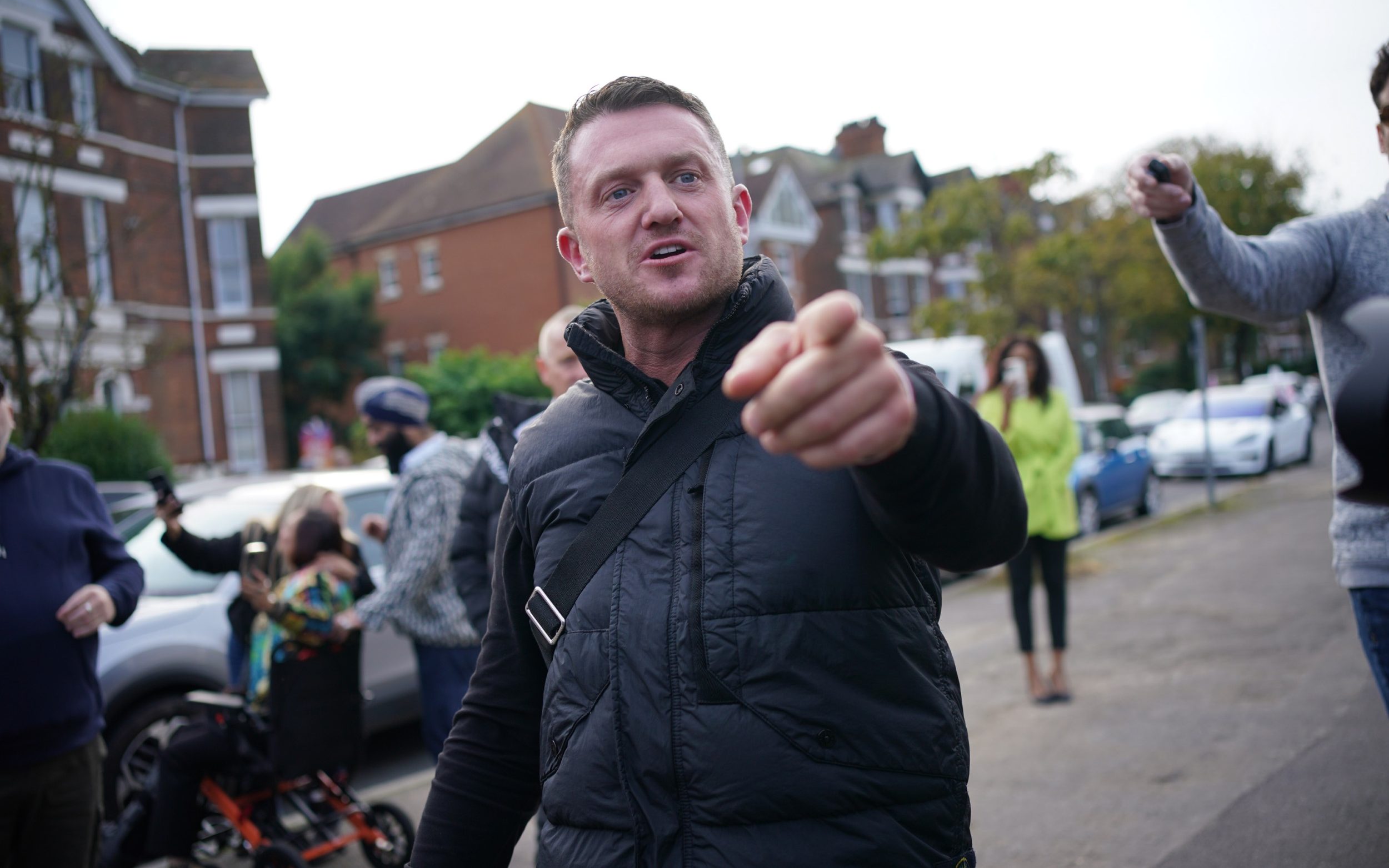 Robinson points at the camera in a street
