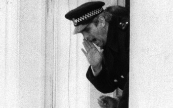 Lock shouting instructions down to police officers below from the Embassy balcony