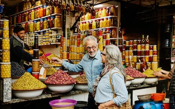senior couple sampling olives at olive stand while exploring the medina of Marrakech during vacation in Morocco