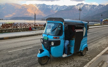 An electric rickshaw glides past Dal Lake in Srinagar, Kashmir's largest city